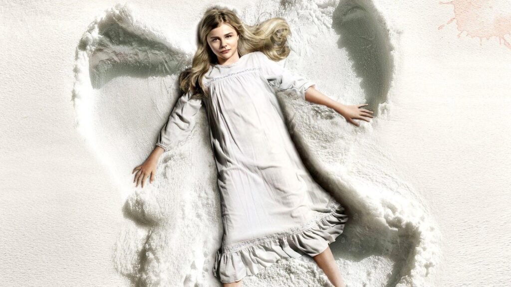 Chloë Grace Moretz as Abby, lying in the snow in her nightdress in the official key art for Let Me In (2010)