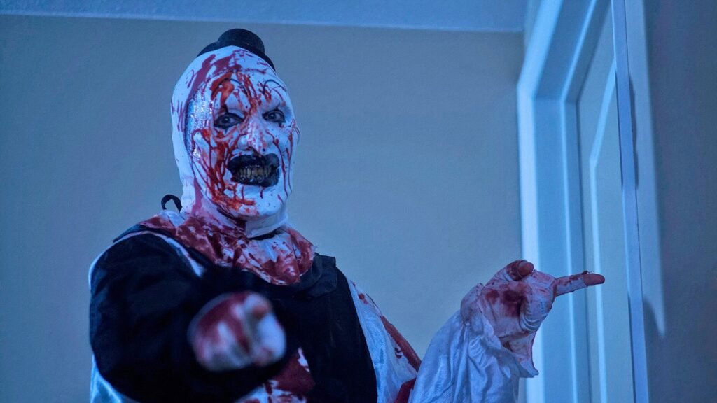 Mike Giannelli as Art the Clown in All Hallows' Eve (2013), blood-covered and pointing in a doorway in the anthology's wraparound finale