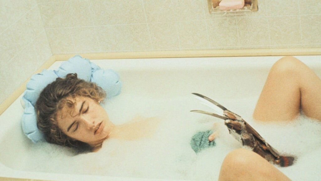Nancy Thompson (Heather Langenkamp) asleep in the bathtub as Freddy Krueger's glove rises from the water in A Nightmare on Elm Street (1984)