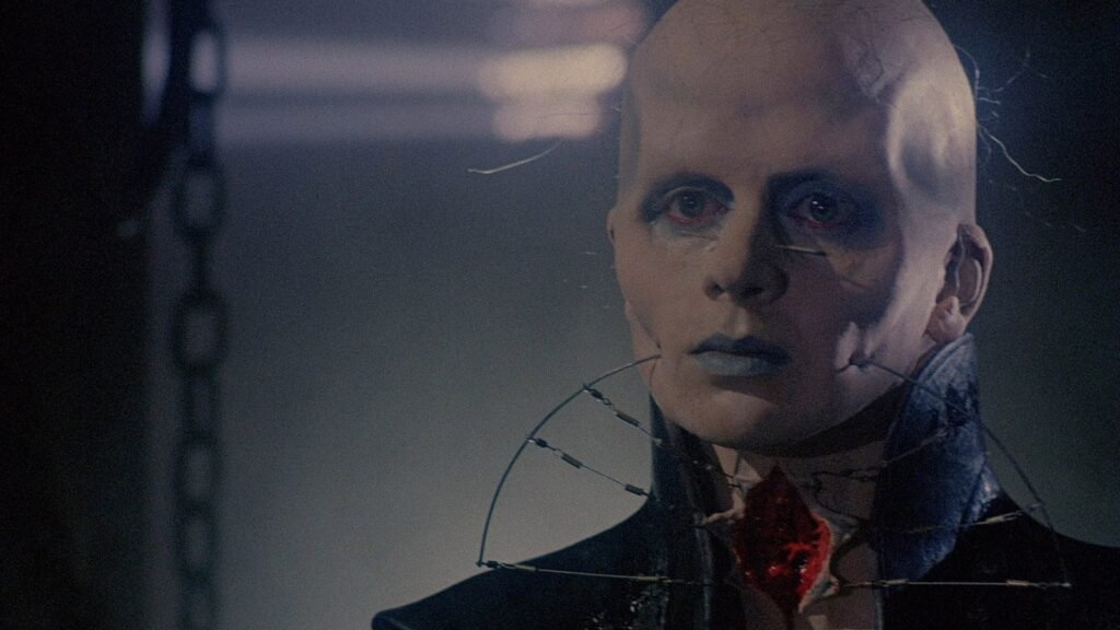 Peter Atkins as the Barbie Cenobite in Hellraiser III: Hell on Earth, in pale Cenobite makeup with barbed wire around his neck